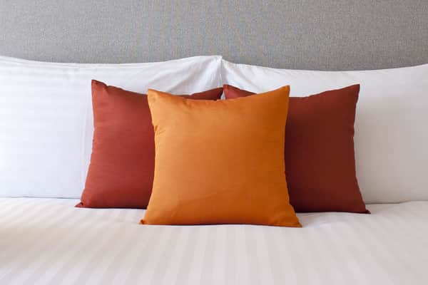 three red pillows on a white bed