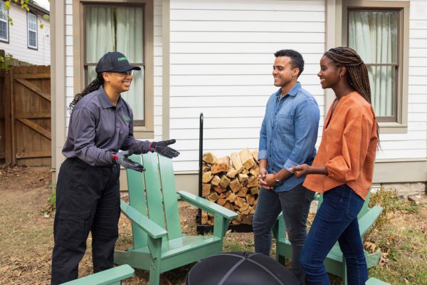 A Terminix wildlife control expert speaking with a couple in their backyard.