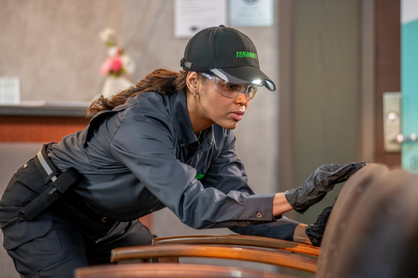 A Terminix technician inspecting the fabric of brown waiting room chairs for commercial bed bug removal.