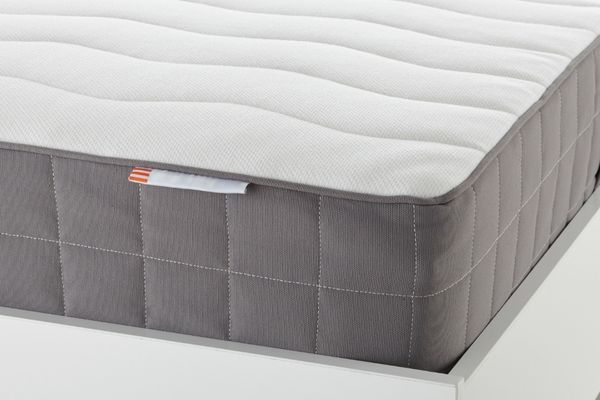 A gray and white quilted mattress on a white bed frame.
