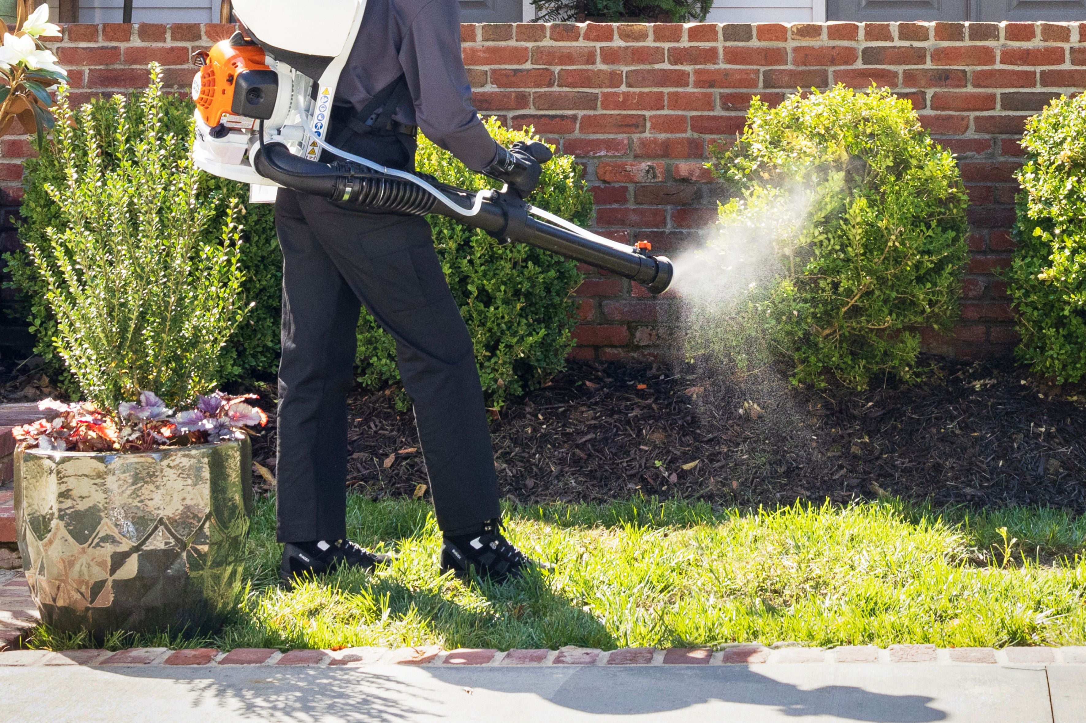 tech spraying pesticides on bush