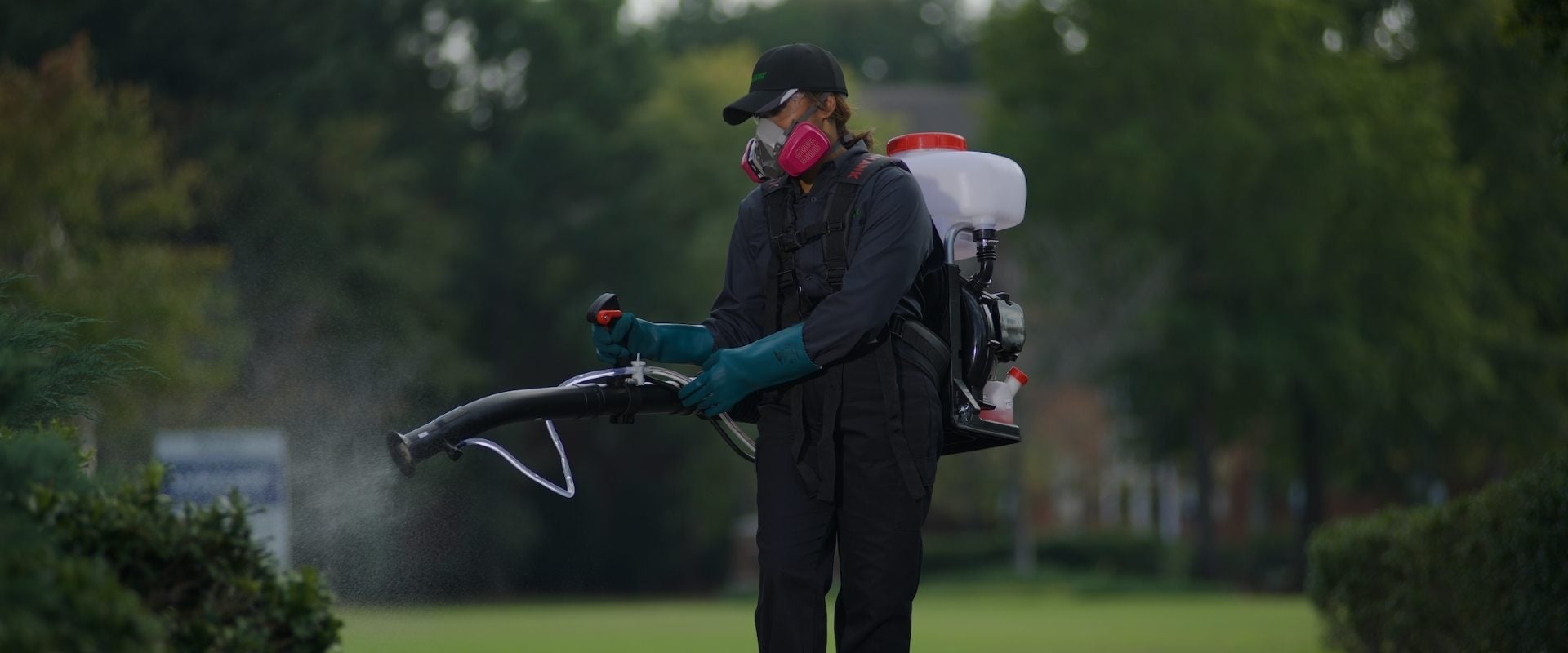 tech spraying pesticides on bush