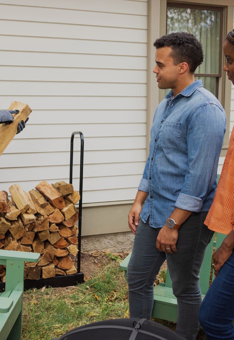 A technician points to a piece of wood while two customers look on